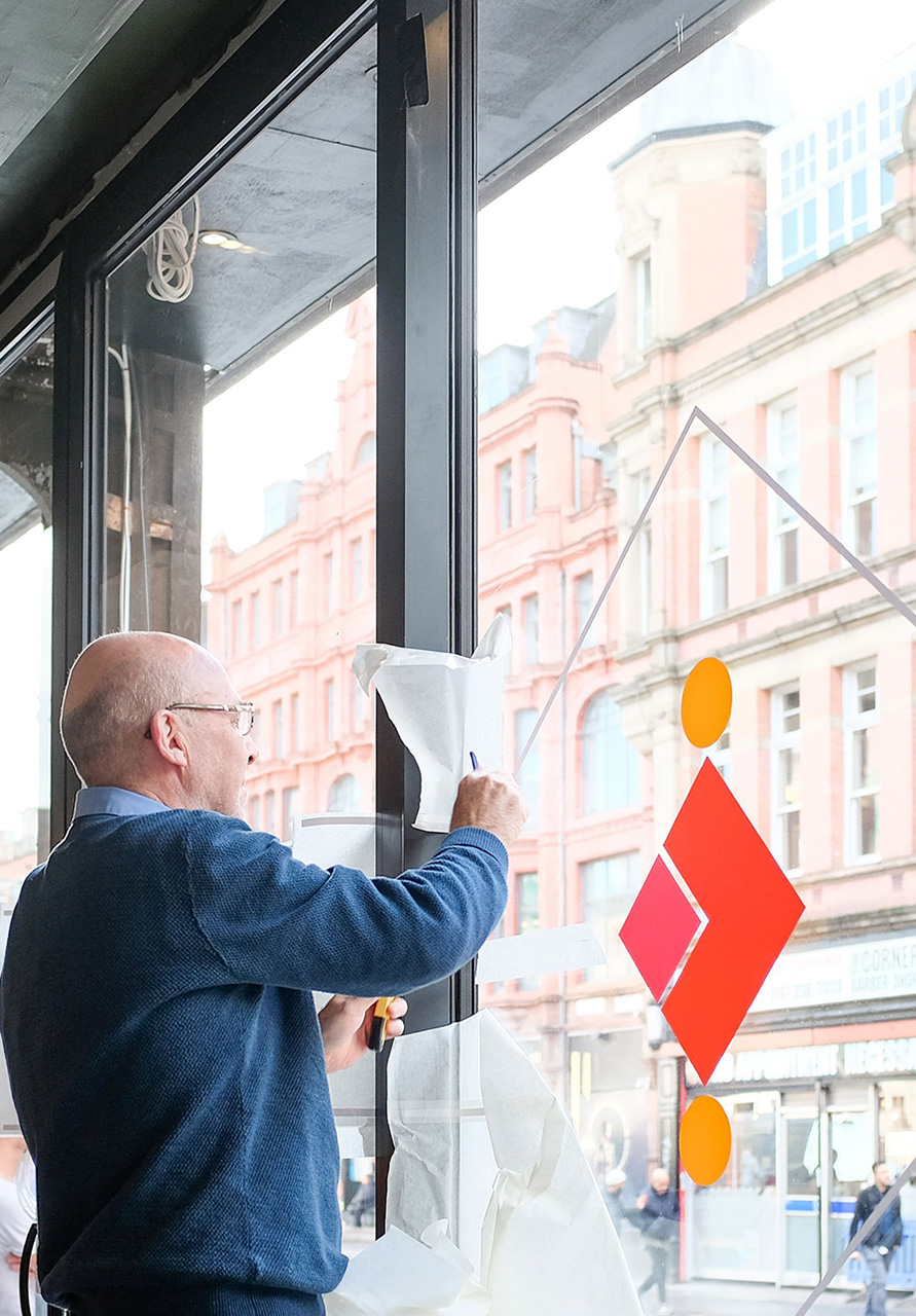 An elderly man applies The Patron vinyl window graphics to the windows.