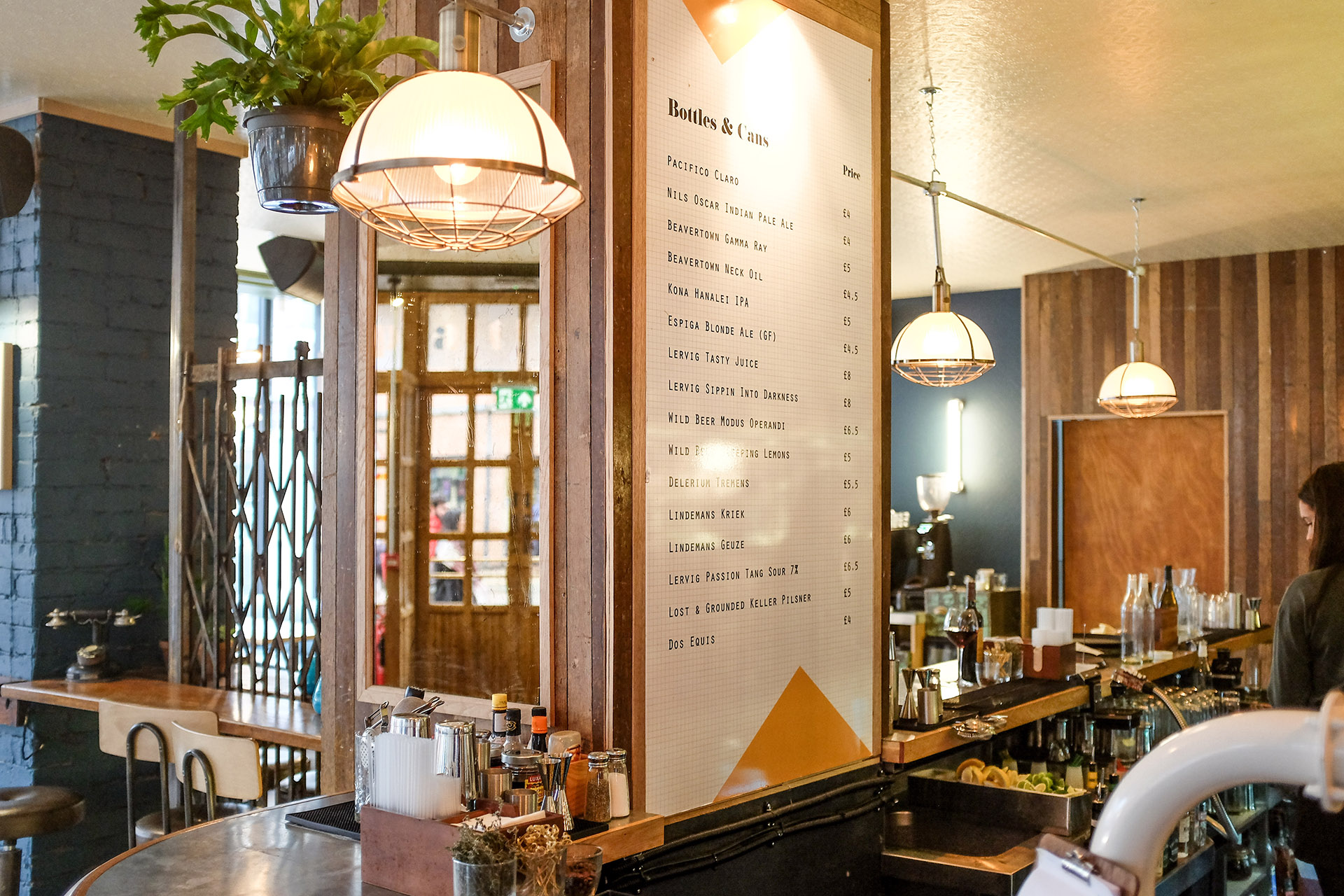 Large menu listing bottles and cans hanging in a bar.