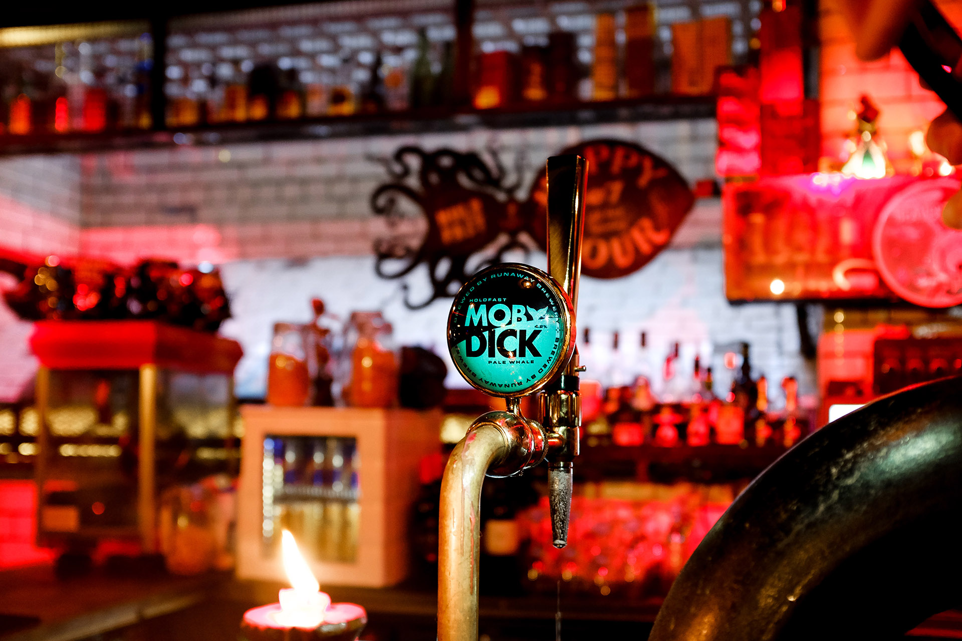 Dimly lit bar featuring a beer pump badge with the Moby Dick design.