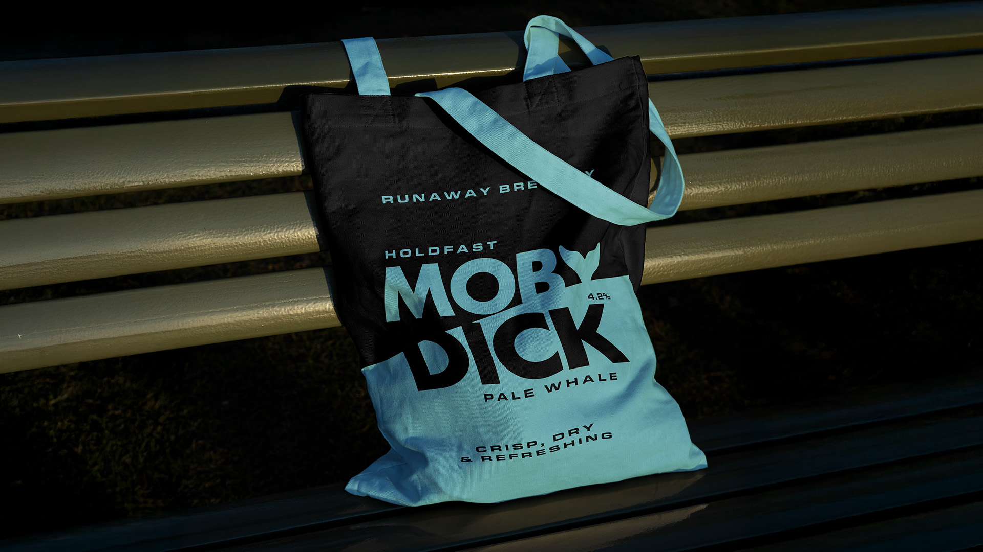 A tote bag with Moby Dick branding slumped on a bench.