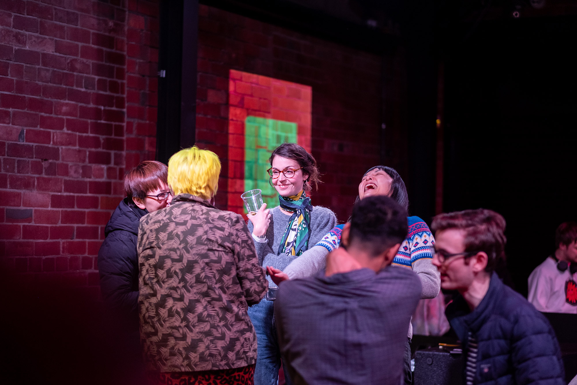 A group of people standing in a circle, talking and laughing.