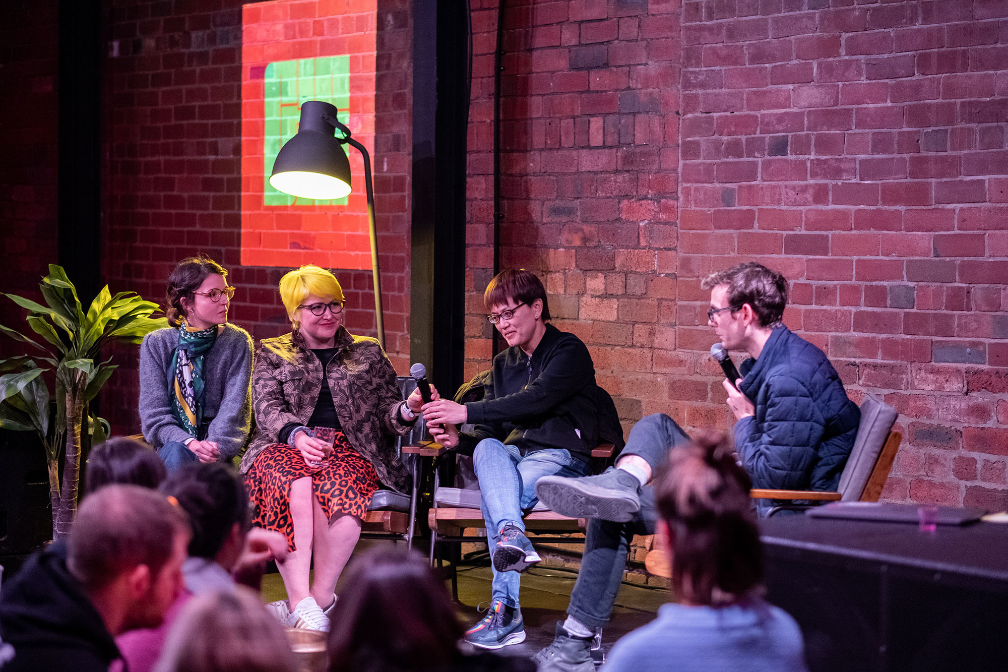 Audience watches a four-person panel discussion on stage, with the Chew the Fat logo projected in the background.