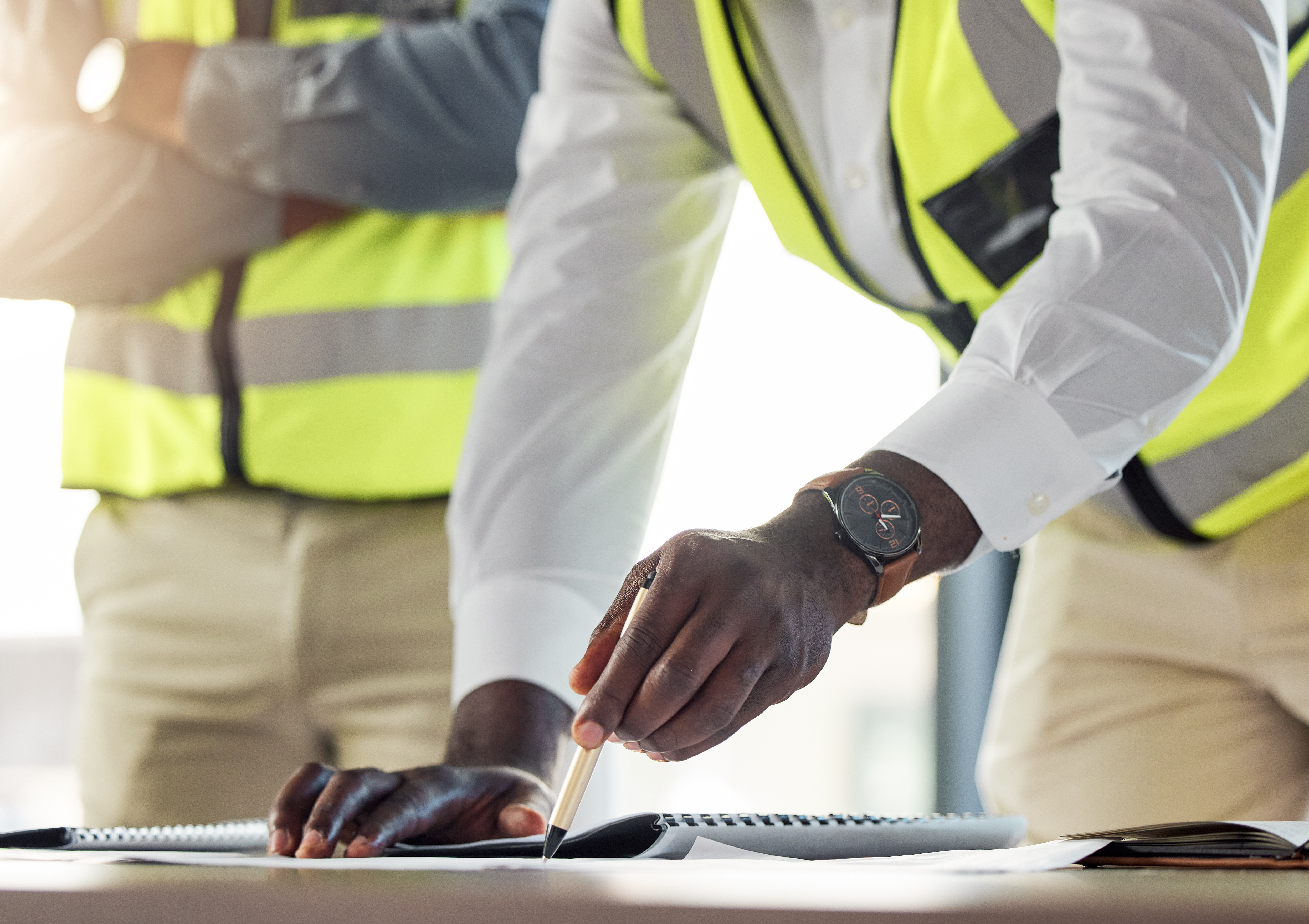 Cut off photo of two men standing over safety plans.