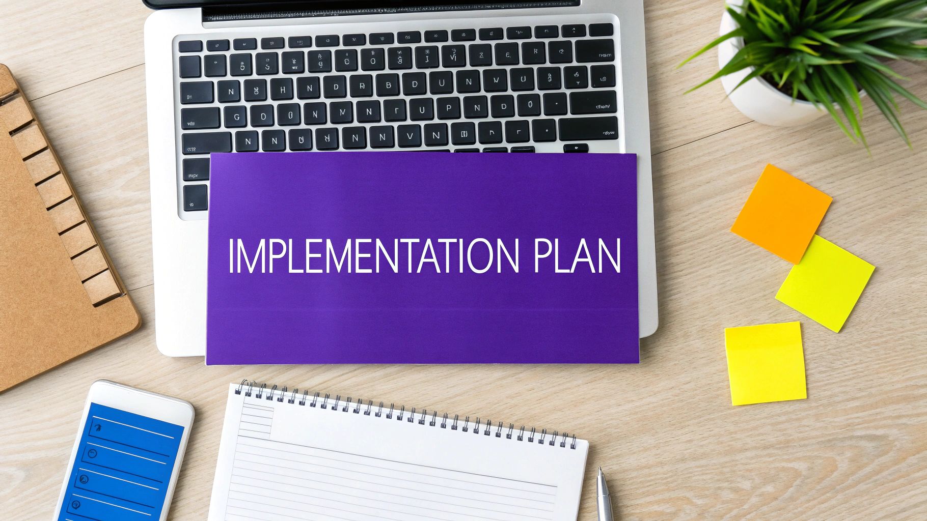 A flat lay of a wooden desk with a laptop, a purple folder labeled 'IMPLEMENTATION PLAN', and office supplies.