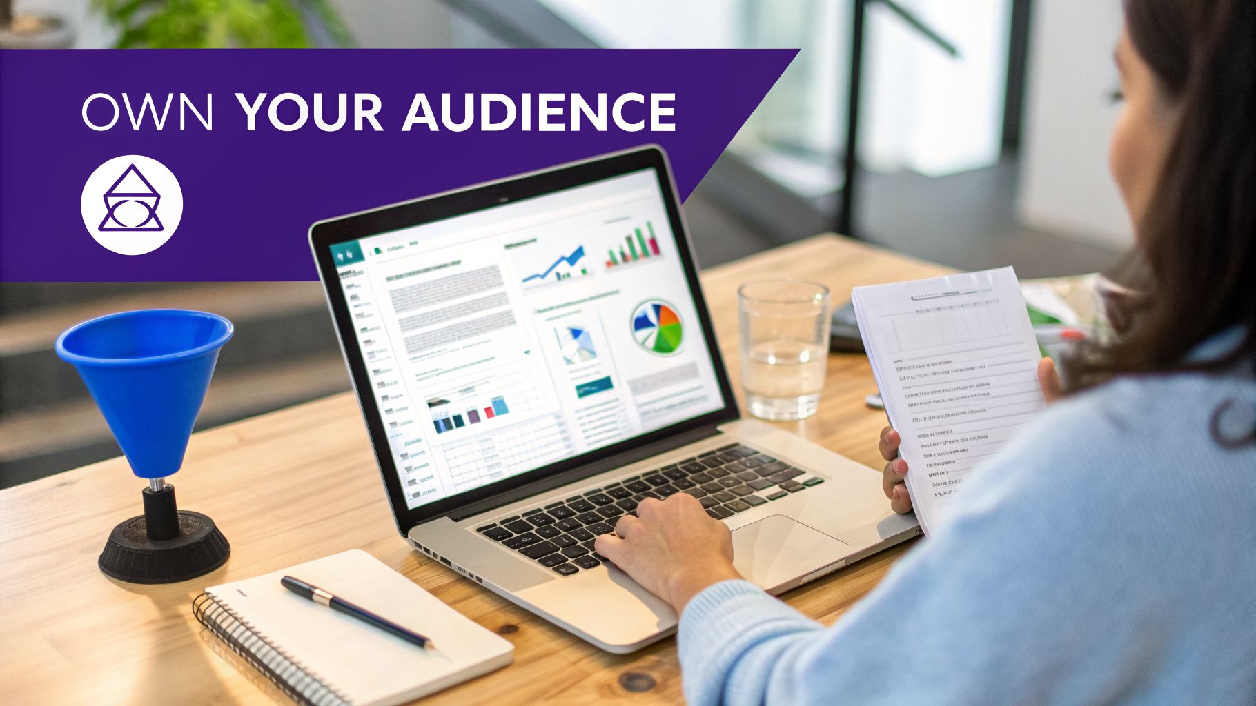 Person working on a laptop displaying data analytics, with a marketing funnel and 'OWN YOUR AUDIENCE' text.