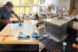 Man polishing a large white kitchen countertop in a sunlit modern kitchen under renovation.