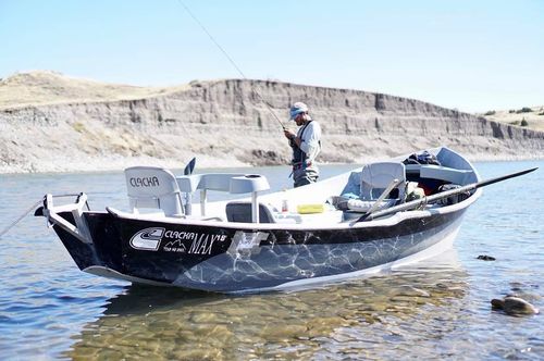 Fishing guide ties on another fly standing behind his drift boat in the Yellowstone River.