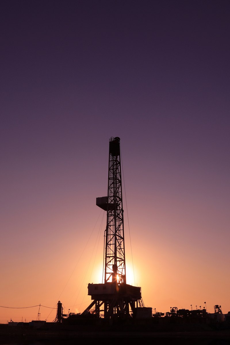 Oil drilling derrick silhouetted against a violet sunset