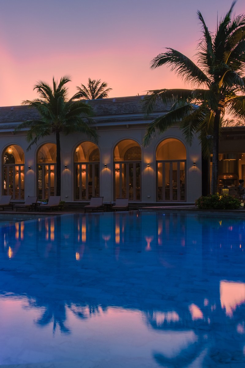 Resort with arched windows beside an infinity pool at sunset