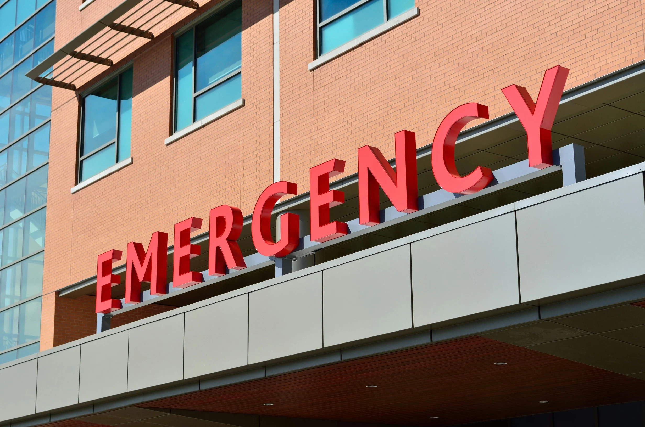 Large red Emergency sign on modern hospital building exterior