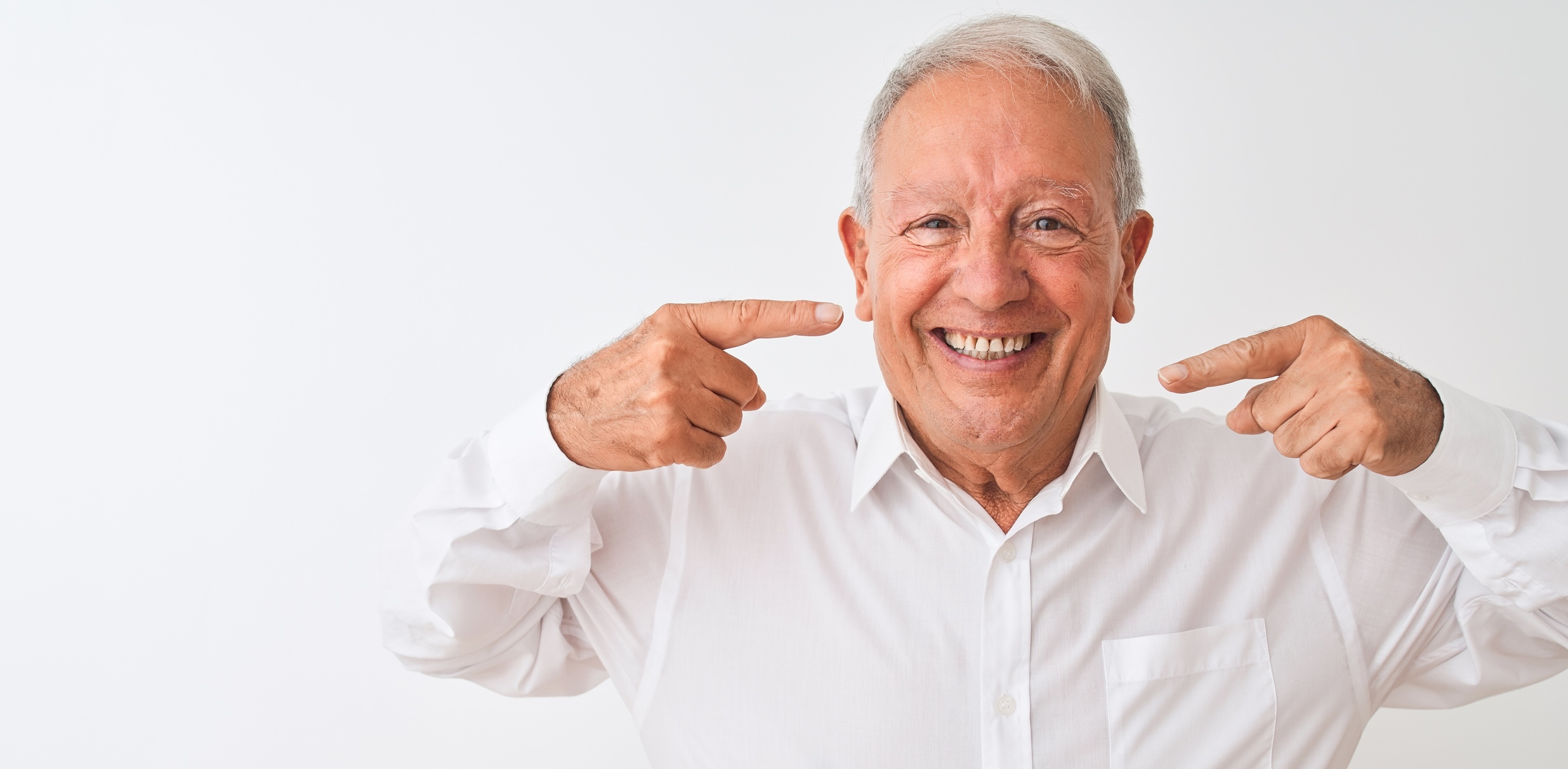 a man pointing to his smile while grinning widely