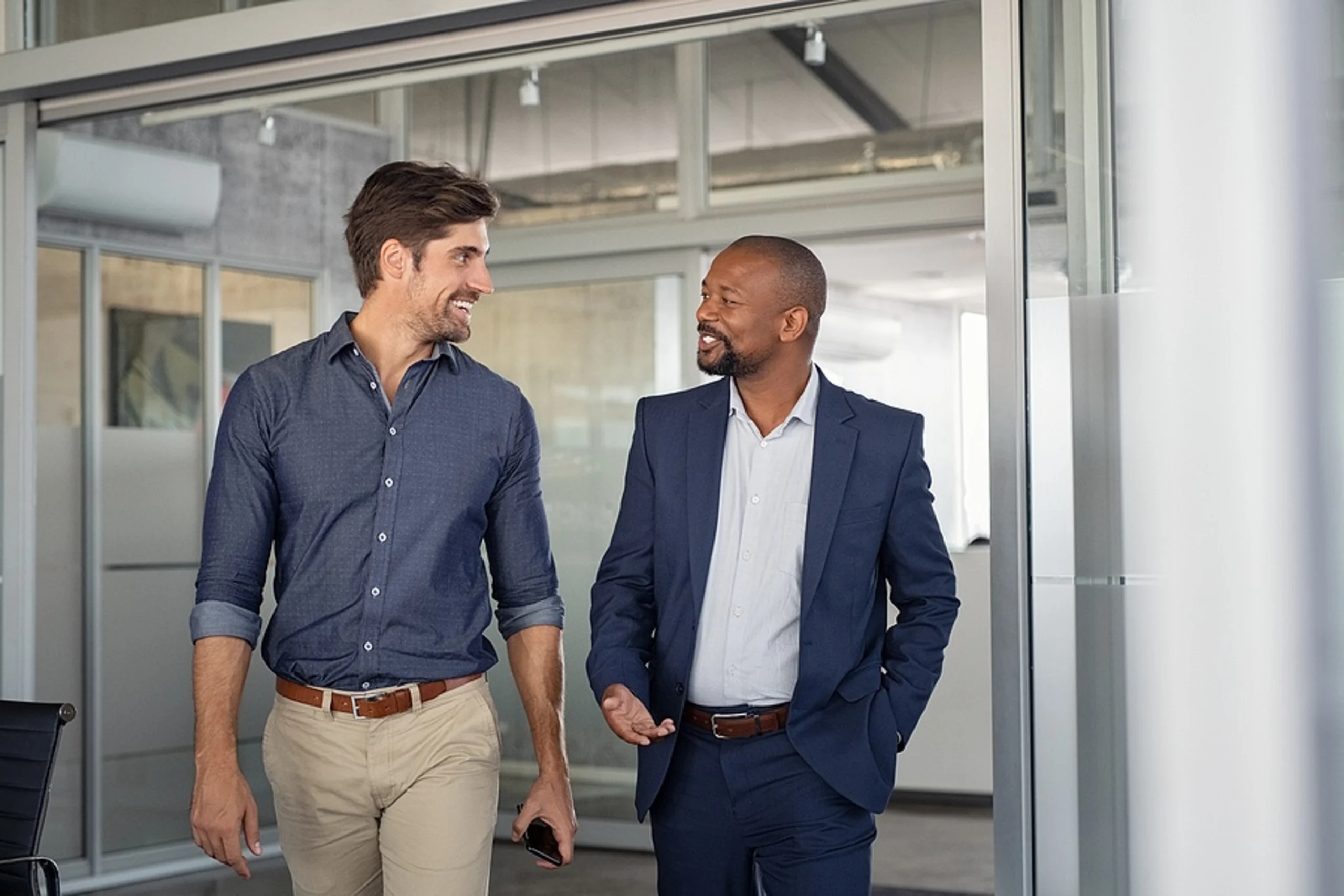 Two businessmen talking and smiling in modern office building