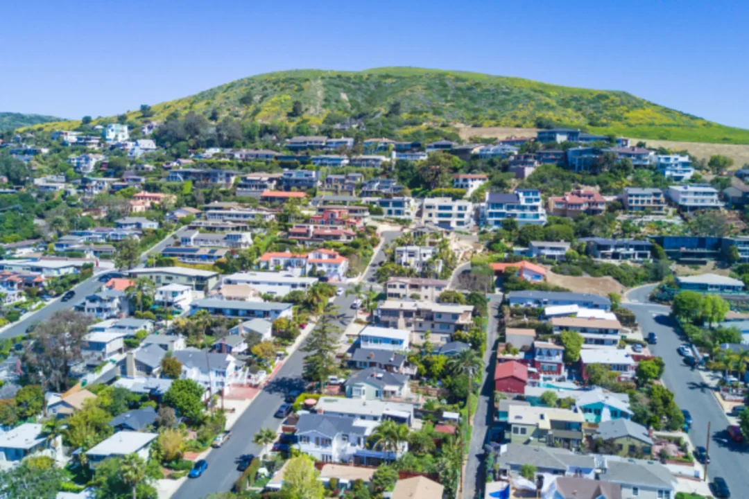 Aerial view of hillside suburban neighborhood with colorful houses and green landscape
