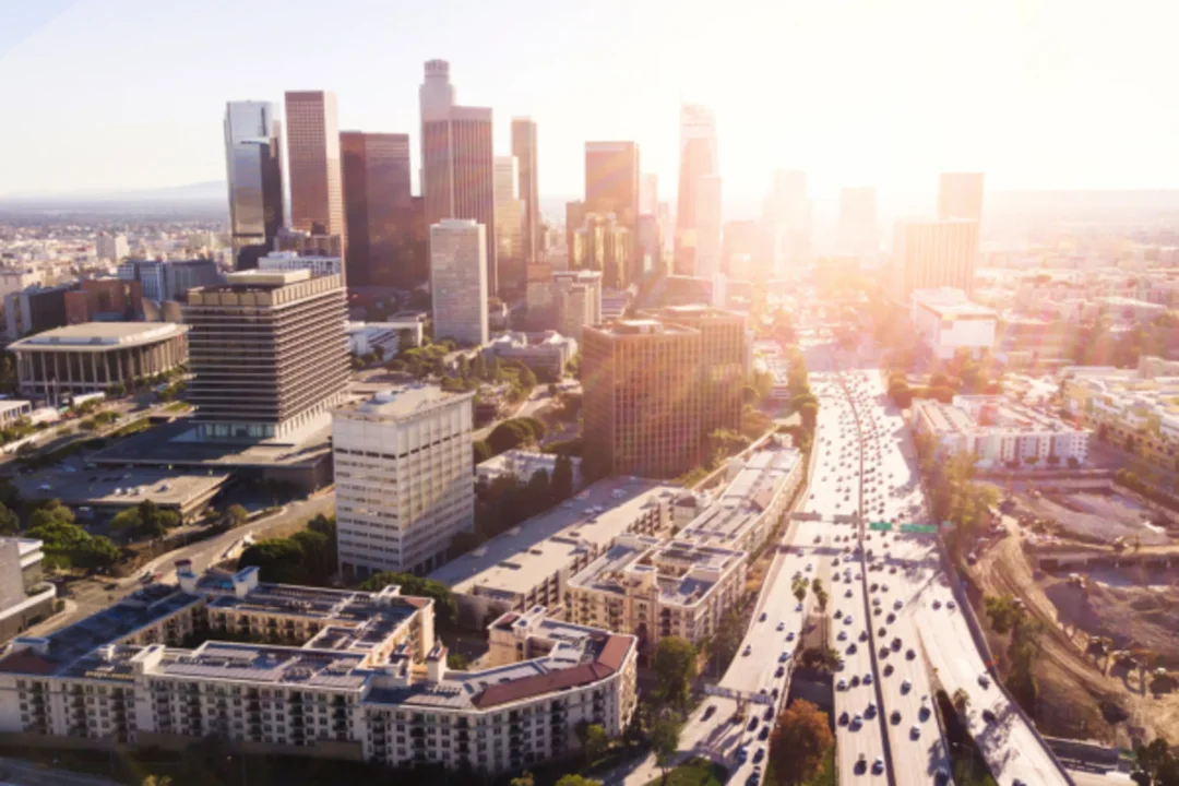 Aerial view of downtown Los Angeles skyline with heavy freeway traffic during golden hour sunset
