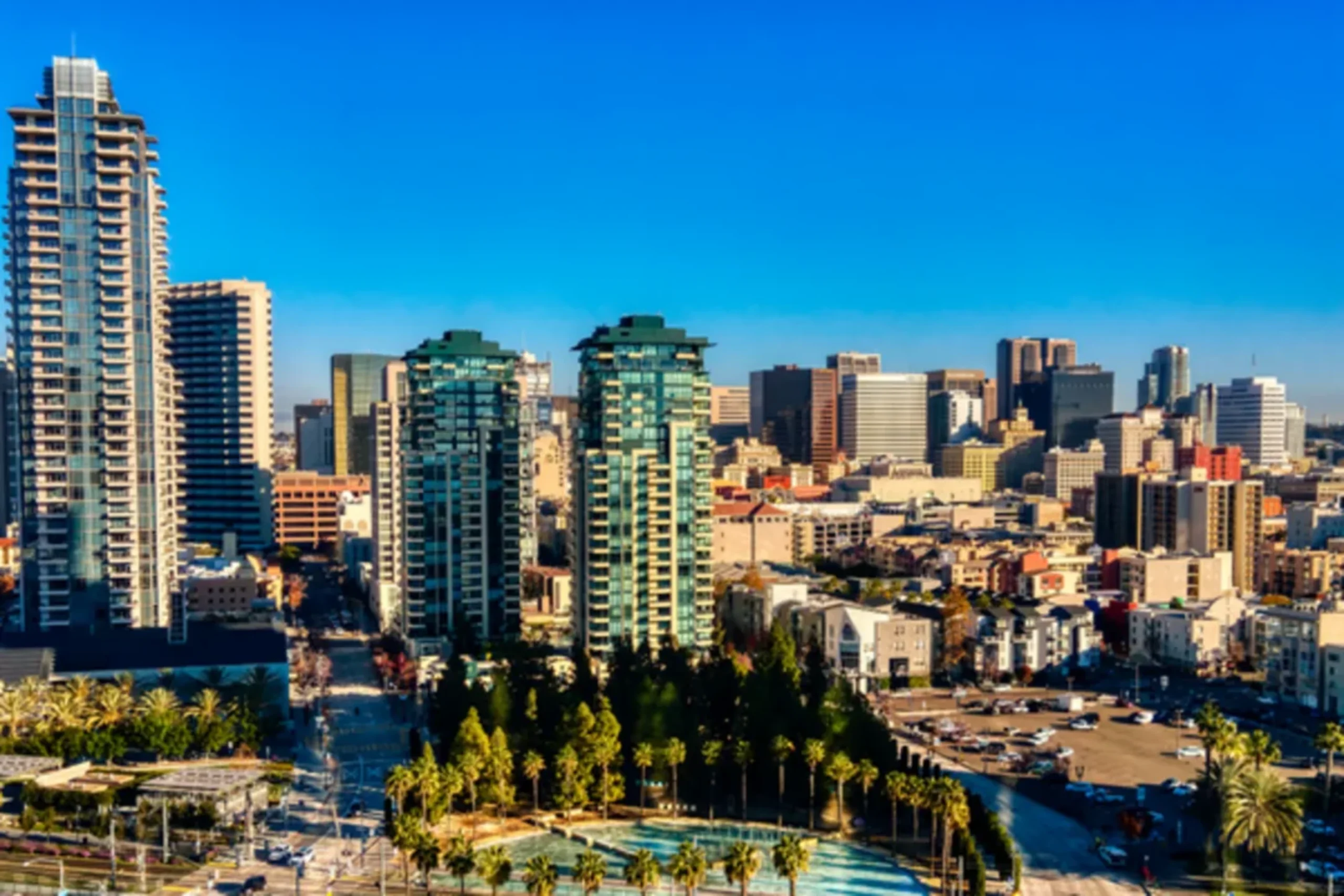 Modern high-rise buildings and palm trees in San Diego's urban skyline under clear blue sky
