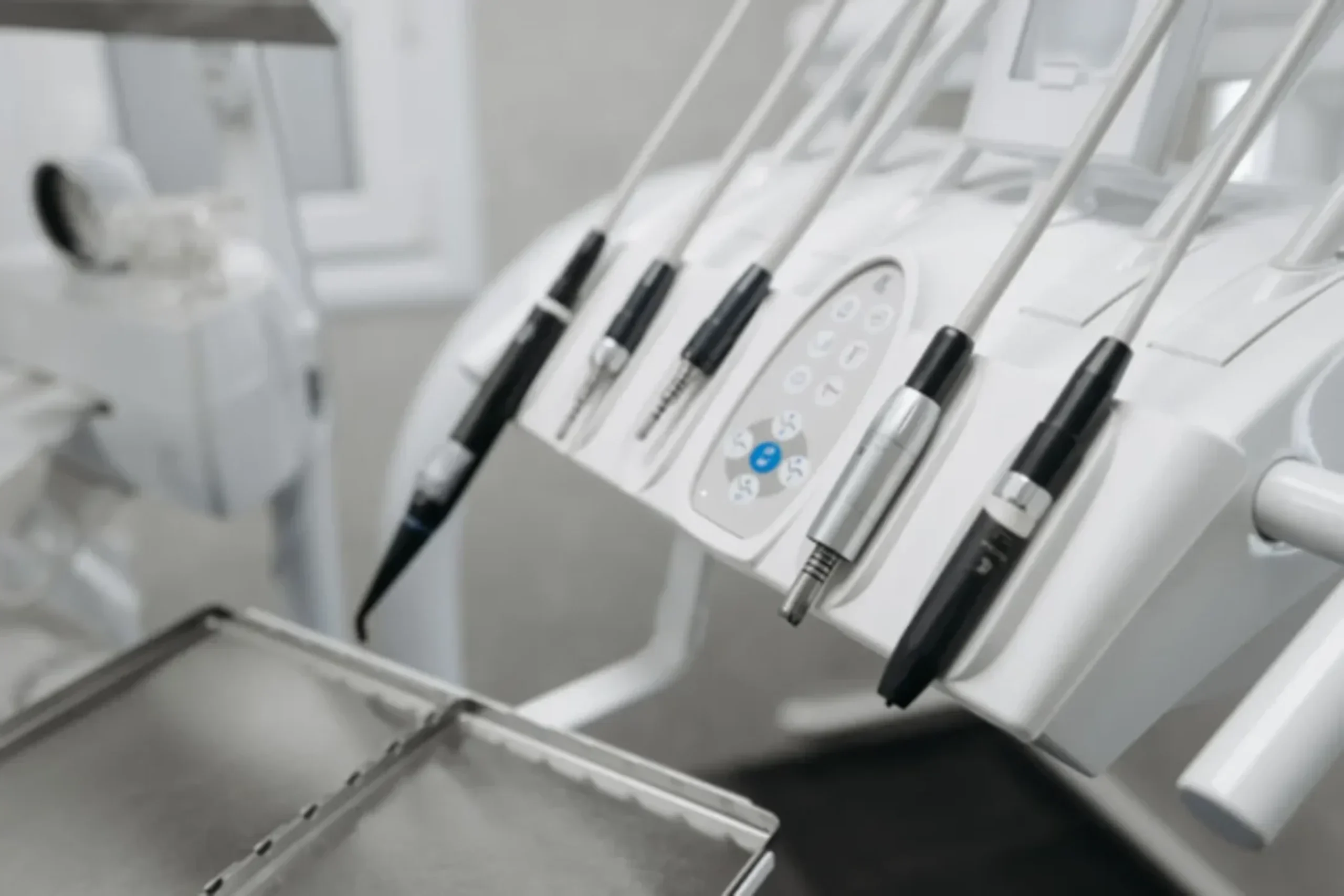 Modern dental office equipment with multiple handpiece tools mounted on white dental unit in clinical setting.