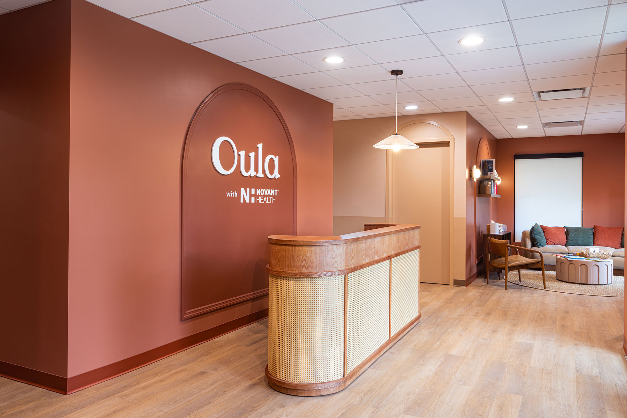 Oula Health Charlotte reception area by Ossa Studio, featuring custom wood millwork, terracotta walls, and Oula signage.