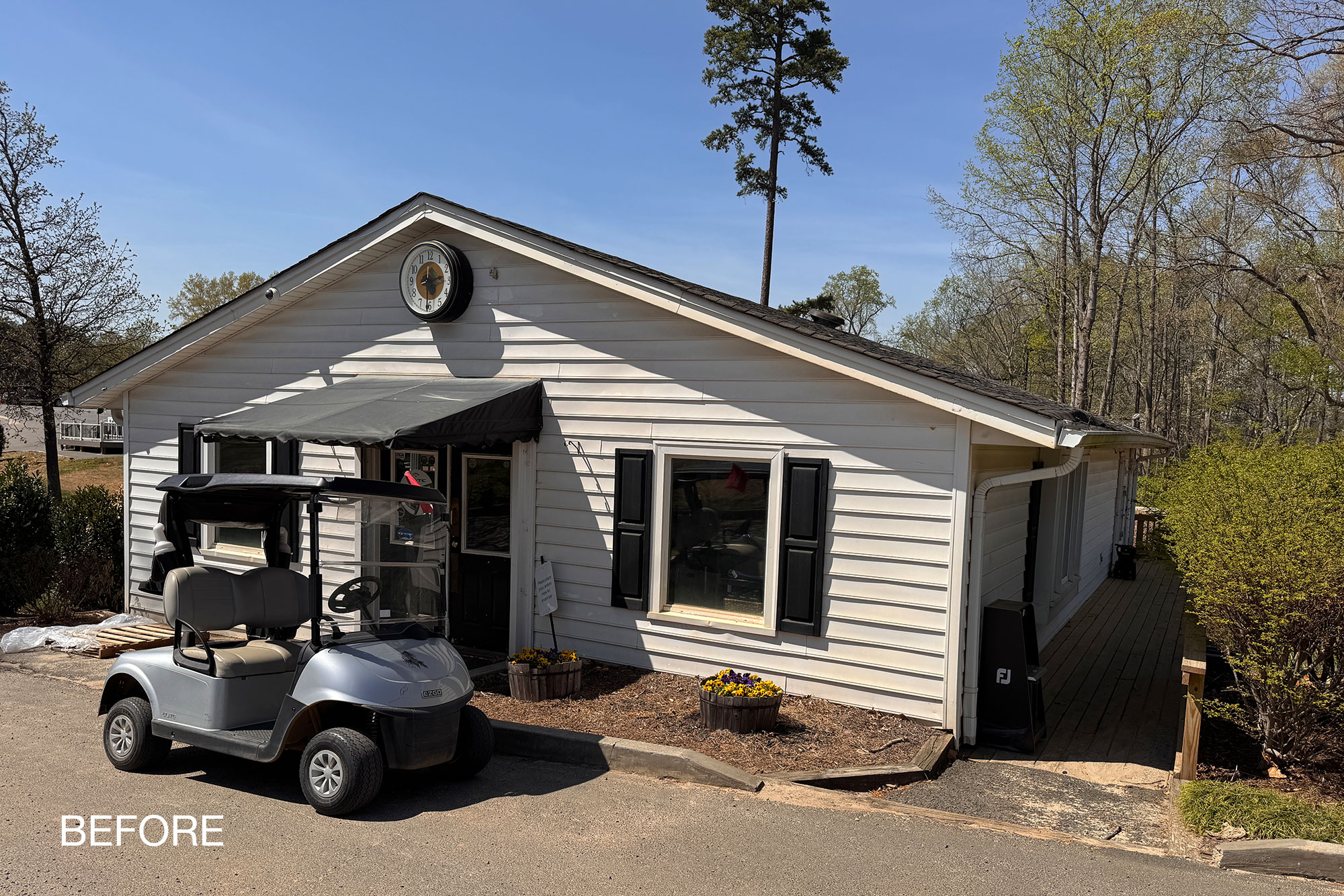 Pine Lake Country Club pro shop before renovation, with white vinyl siding, black shutters and a fabric awning.