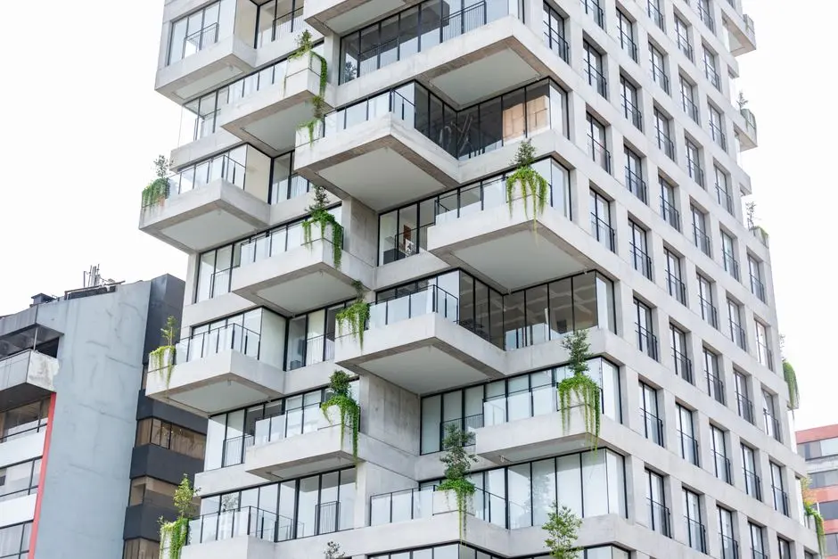 Contemporary residential building with plants on balconies, showcasing sustainable urban living in a vibrant cityscape.