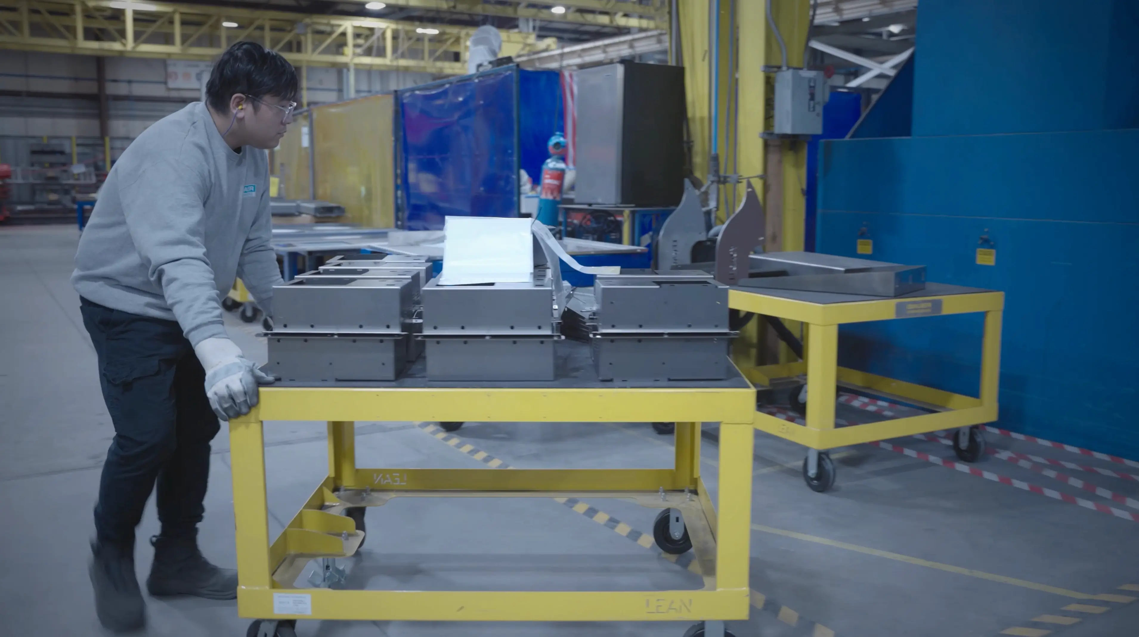 Operator utilizing rolling pallet carts to transport metal parts