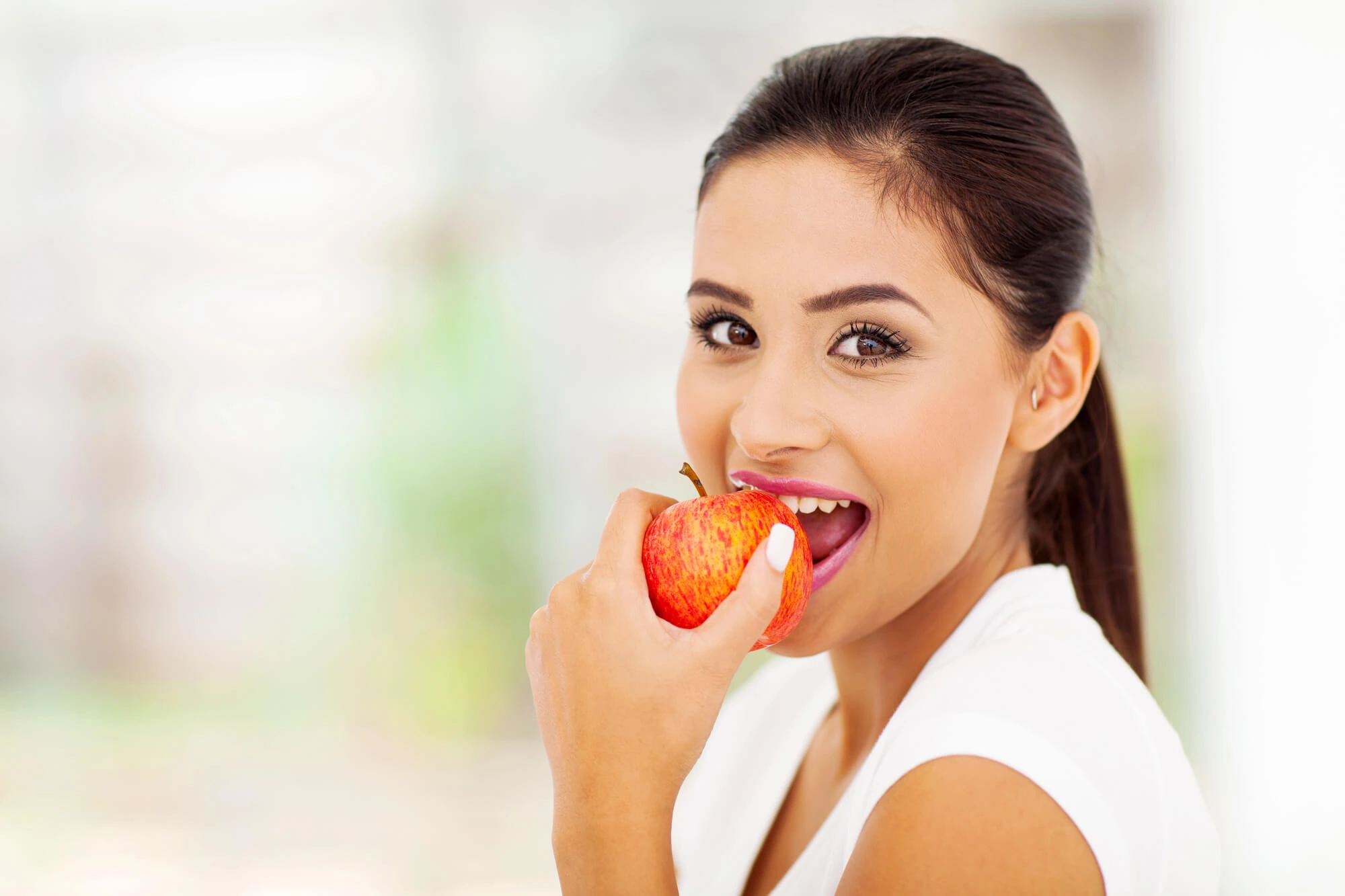 woman eating an apple after teeth cleaning in fairfax