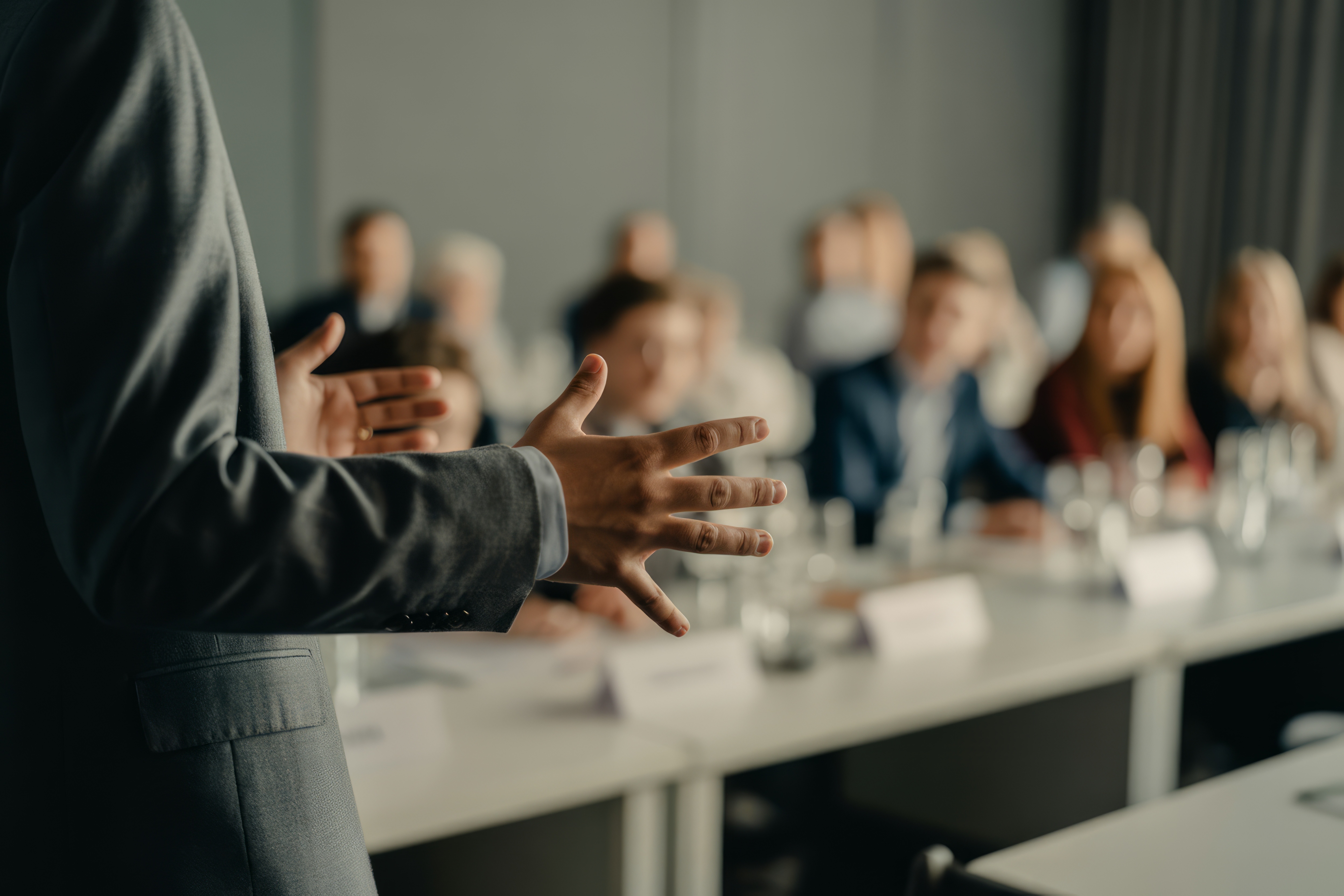 Close-up of a business professional giving a presentation to a seated audience, emphasizing leadership, communication, and public speaking in a corporate setting.