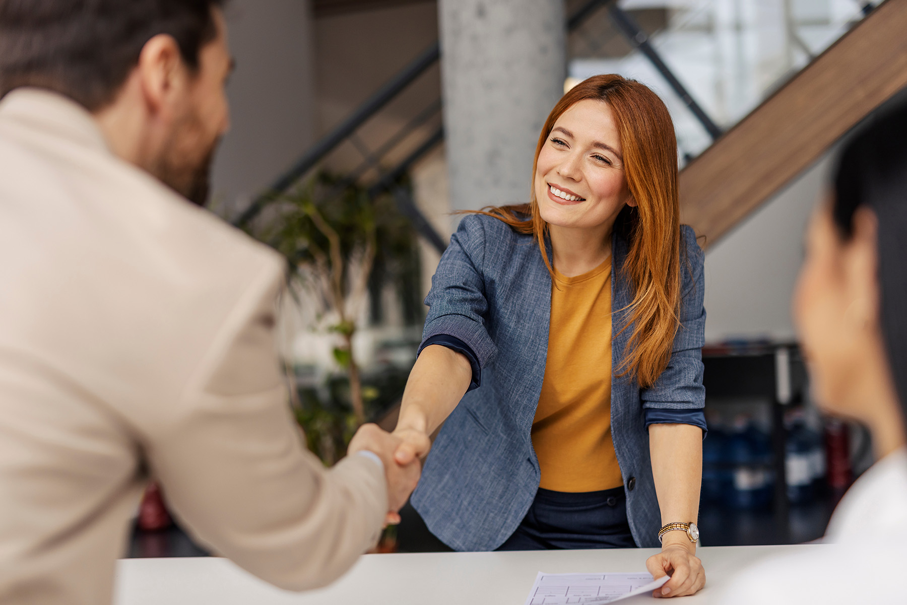Candidate shaking hands with a hiring manager after a successful job offer discussion in a professional office setting.