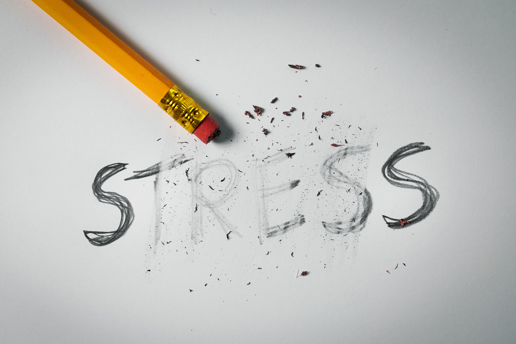 Pencil erasing the word “stress” on paper, symbolizing stress relief, burnout recovery, and mental wellness.