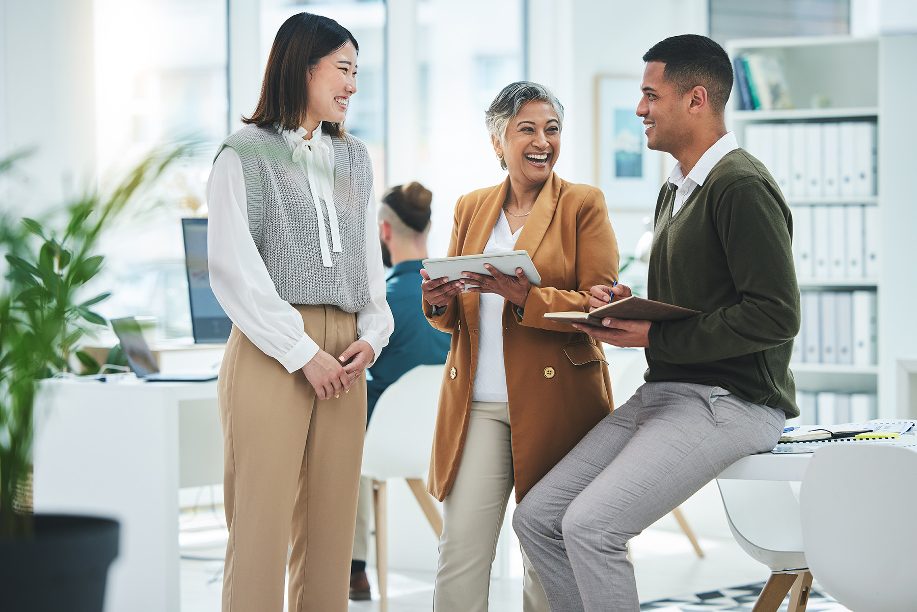 Diverse professionals collaborating and smiling together in a modern office during a team discussion.
