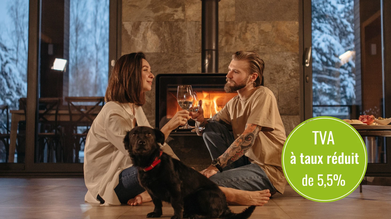 Un couple assis près d'une cheminée avec un chien noir, avec le logo TVA taux réduit 5,5%