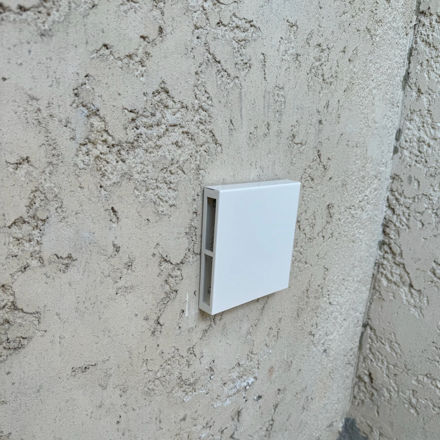 Création d'arrivée d'air blanche rectangulaire montée sur un mur texturé beige clair.