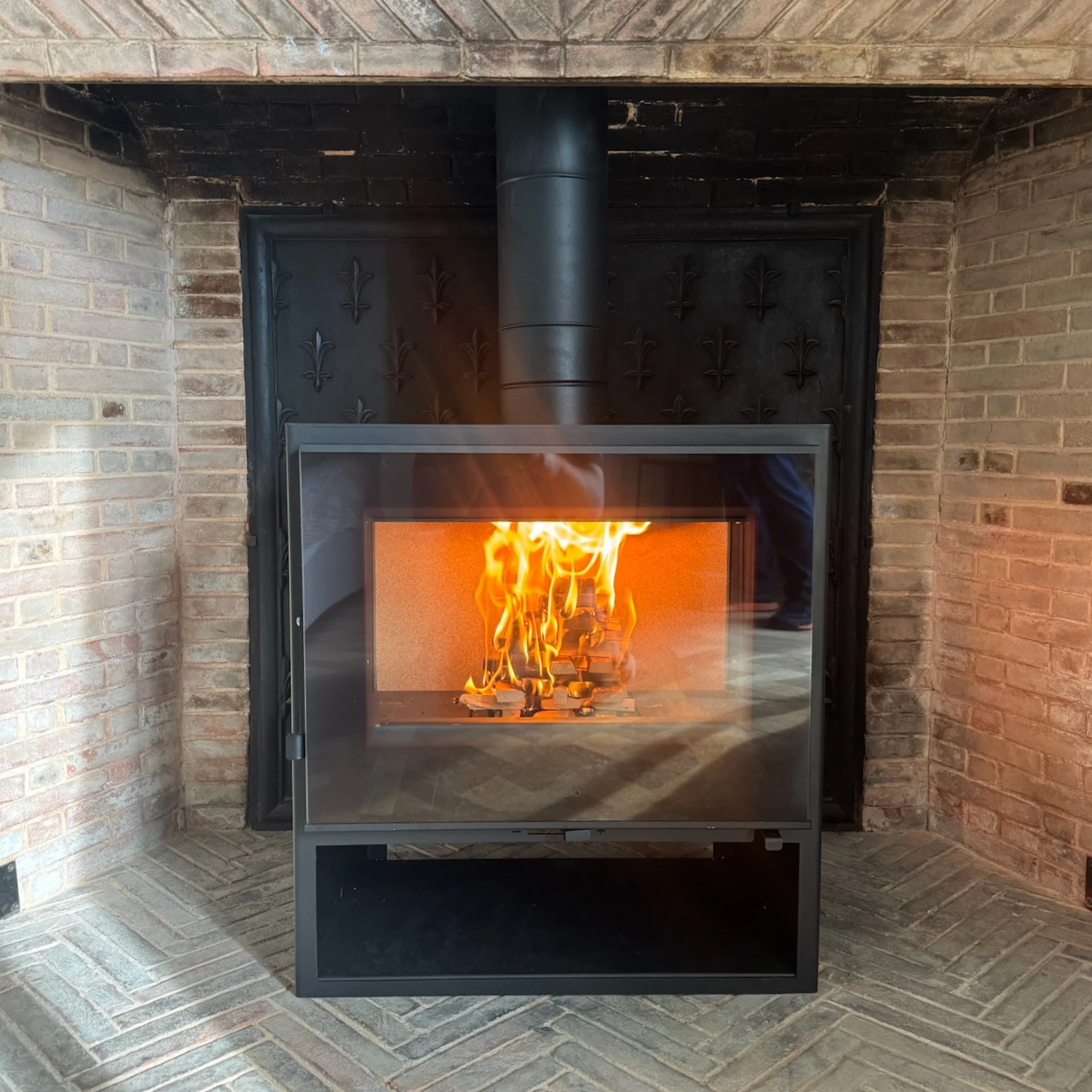 Insert de cheminée moderne allumé avec des bûches en flammes derrière une vitre.