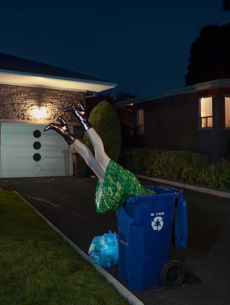 Legs sticking out of a recycling bin at night