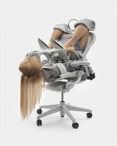 Figure folded into an office chair, long hair hanging to the floor