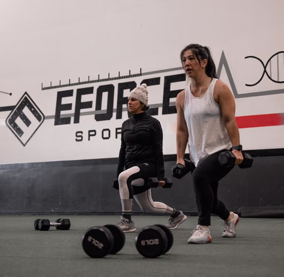 A man and a woman in a gym with kettles.