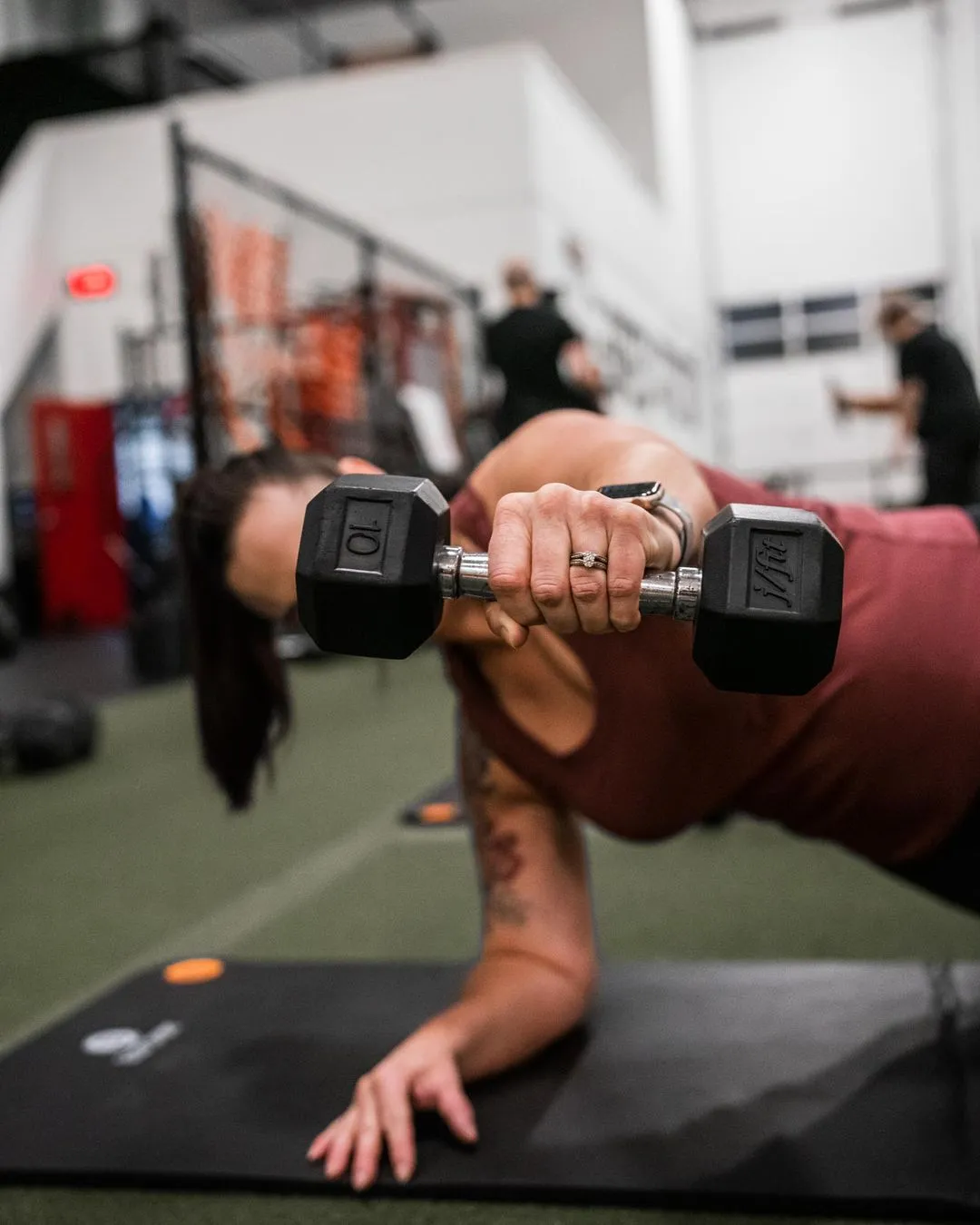 A woman doing a push up with a barbell.