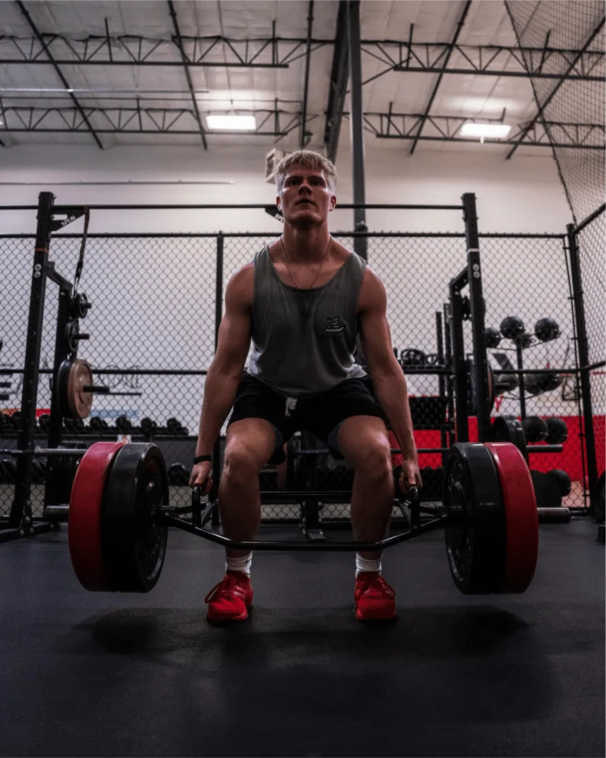 A man sitting on a barbell in a gym.