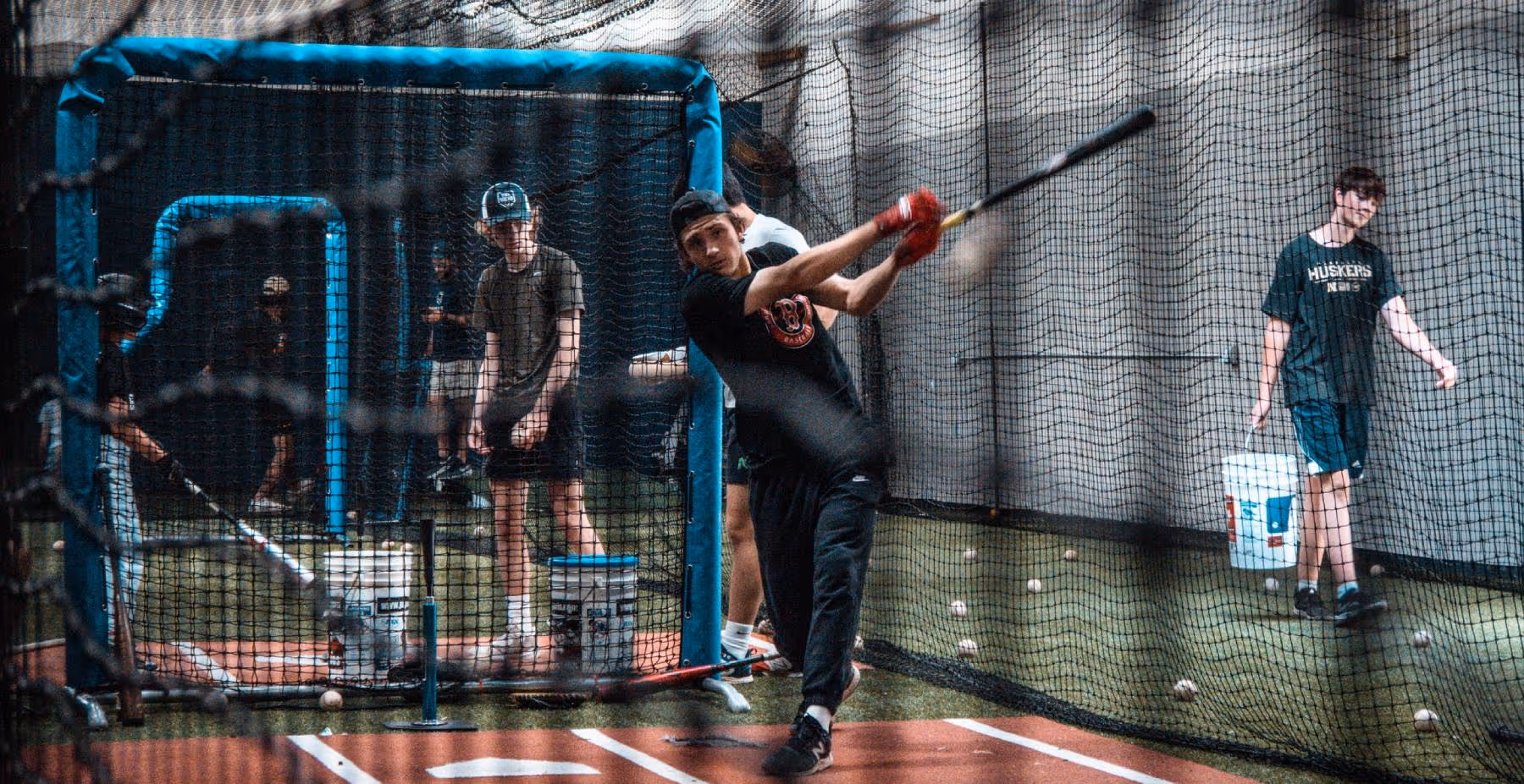 A man swinging a baseball bat in a batting cage.