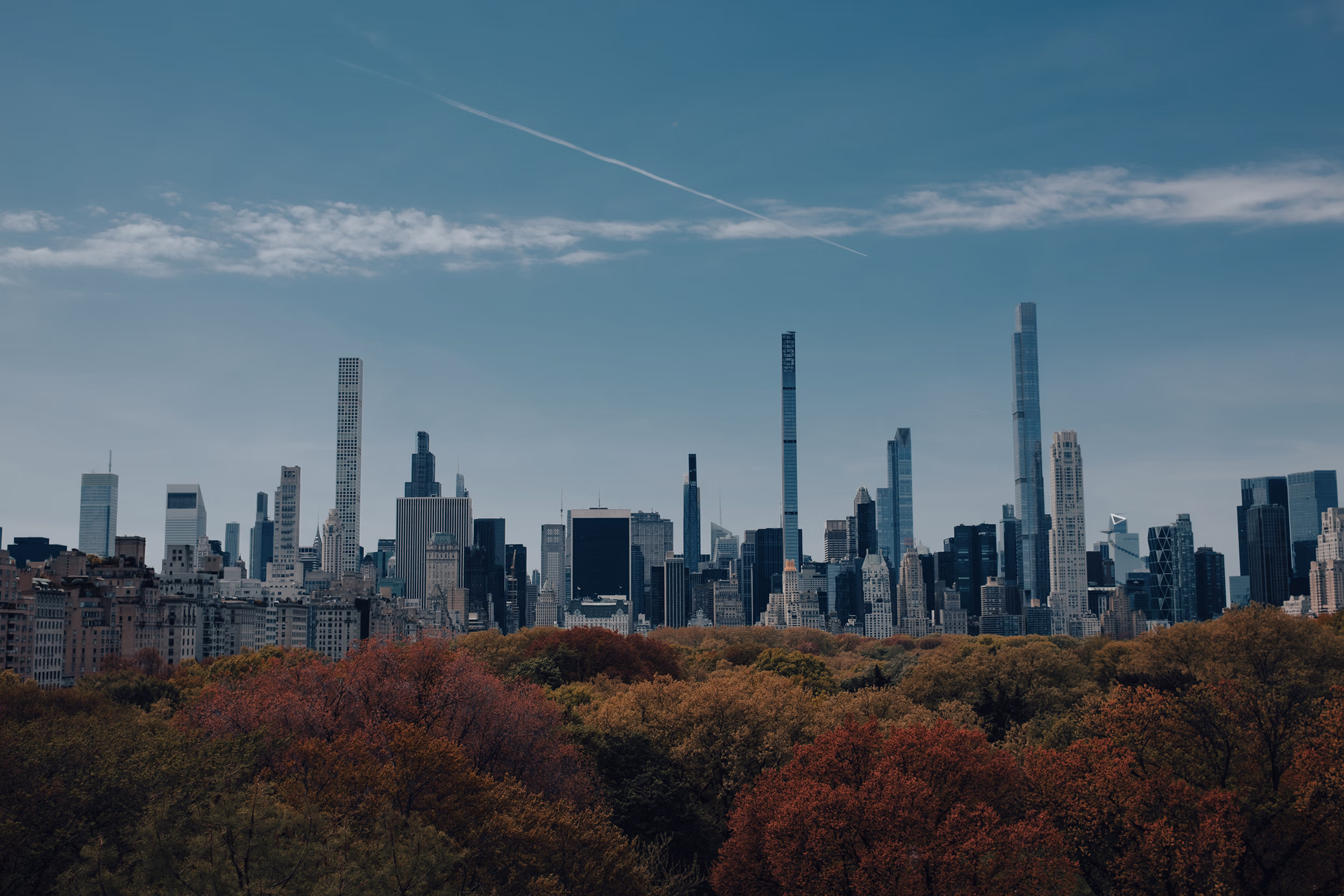 Cinematic landscape photograph of the New York City skyline and Central Park autumn foliage under a bright blue sky - NYC photoshoot booking.