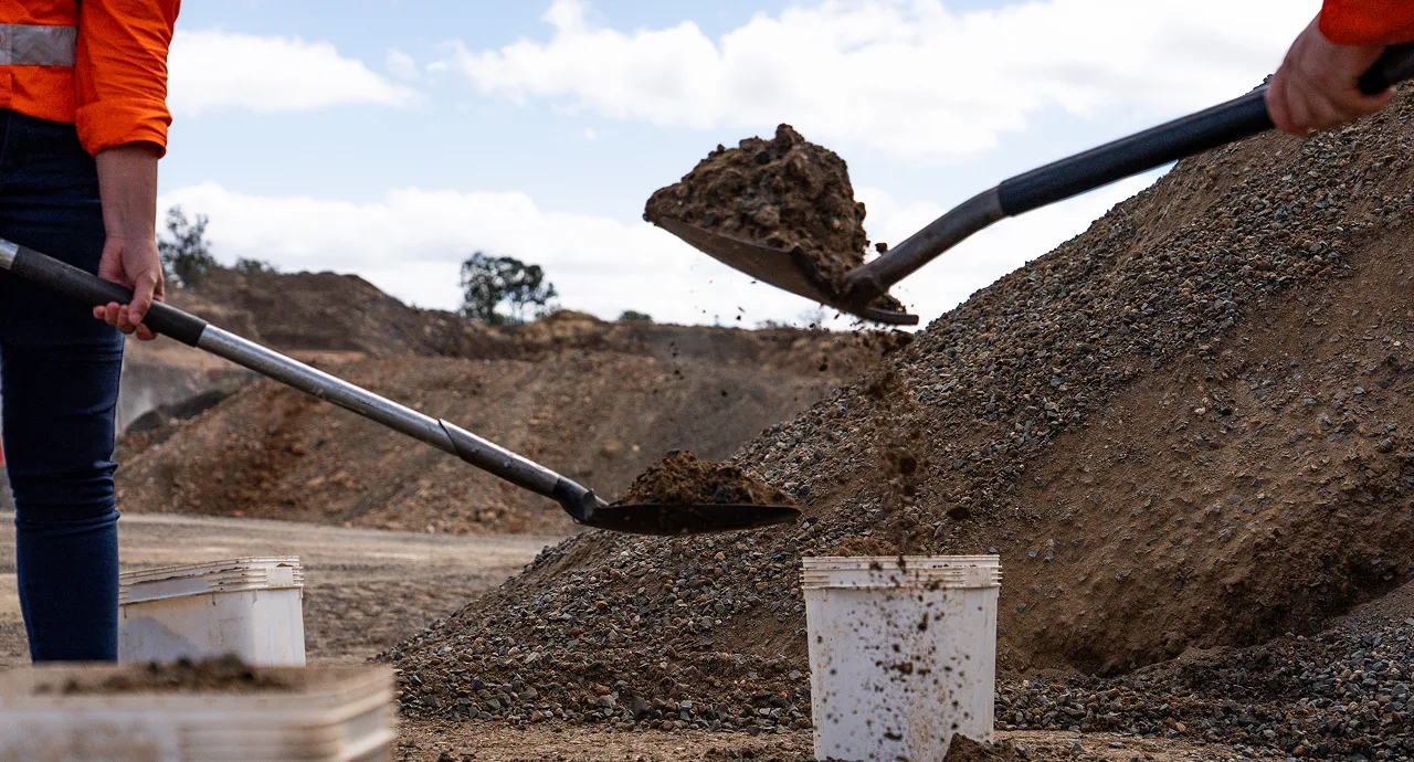 Technician performing soil sampling and site testing using shovel during field work