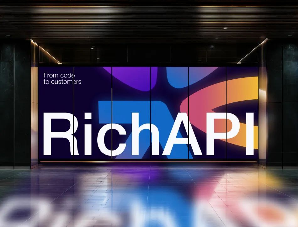 Monitor displaying "RichAPI" branding in large white text with colorful gradient abstract shapes in the background