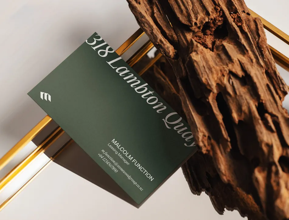 Green business card with gold foil text reading "A Landlord Club" next to yellow pencils on a textured brown wooden surface