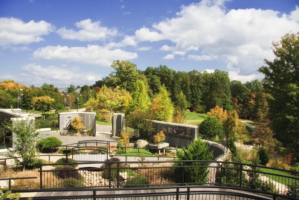 Scenic view of North Carolina Arboretum with autumn-colored trees, landscaped gardens, and clear skies.
