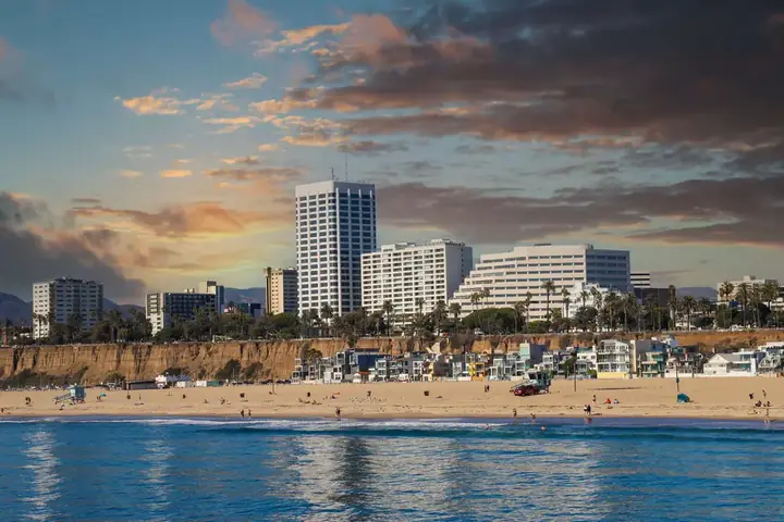 Seaside view of Ramada Plaza by Wyndham with beachgoers, ocean forefront, and a sunset sky.