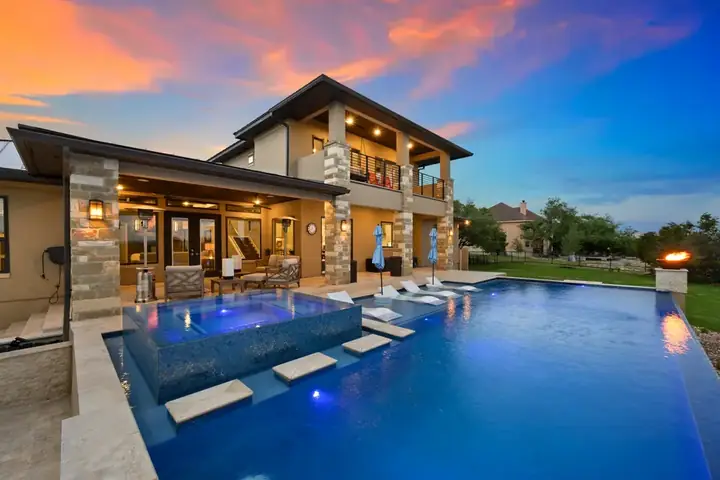 Luxurious Sanderling Resort villa at dusk with illuminated infinity pool and fire feature, reflecting the vibrant sunset sky.