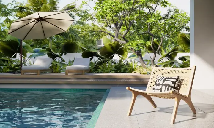 Tranquil poolside lounging area with wooden chair and sun umbrella at Ocean Reef Resort, surrounded by lush greenery.