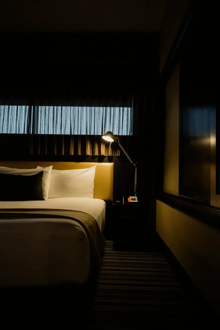Well-appointed guest room with comfortable bed, wall-mounted reading lamp, and striped carpet at Courtyard by Marriott Raleigh North.