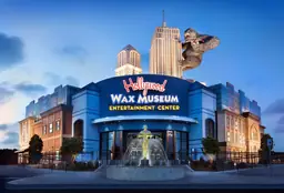 Twilight view of Hollywood Wax Museum with a King Kong figure on the facade and a fountain at the entrance.