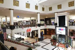 Interior of Crabtree Valley Mall showing multi-level shopping areas with stores like Belk and H&M.