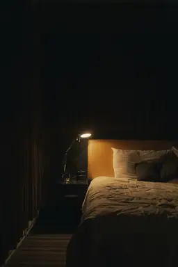 Cozy hotel room at La Quinta Inn & Suites with warmly lit bedside lamp, inviting bed, and nightstand.
